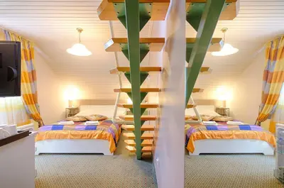 a bedroom with two beds and a spiral staircase at Penzion Park in Laško