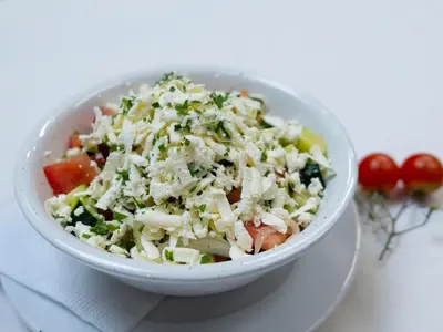 a bowl of coleslaw on a plate with tomatoes at Penzion Park in Laško