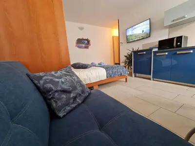 a living room with a blue couch and a bed at Restaurant & Apartments Getaway Pri Kobalu in Vipava