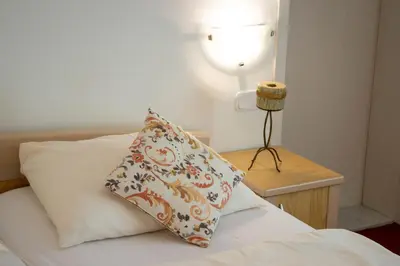 a pillow on a bed with a lamp on a night stand at Rooms Cvitar - Center in Kranjska Gora