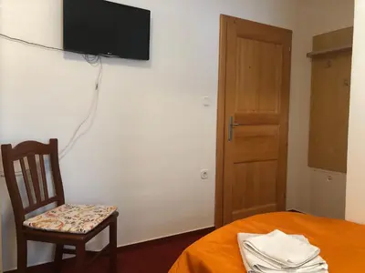 a room with a chair and a television on a wall at Rooms Cvitar - Center in Kranjska Gora