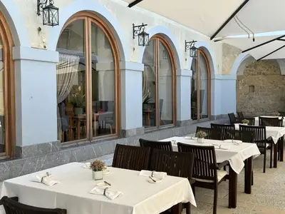 a restaurant with white tables and chairs and windows at Hotel Grad Otočec - Relais Chateaux in Otočec