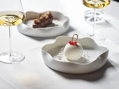 a table with two plates of food and glasses of wine at Hotel Grad Otočec - Relais Chateaux in Otočec
