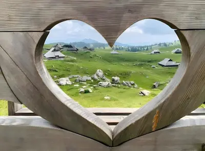 a view of a field through a heart shaped window at Chalet Kanja Velika Planina in Stahovica
