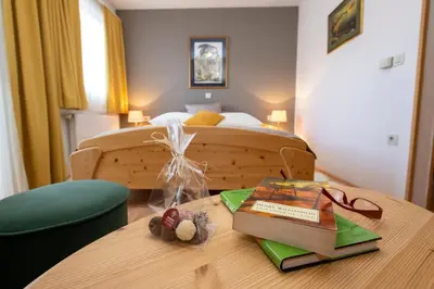 a bedroom with a bed and a table with books at Art Hotel Kristal in Bohinj