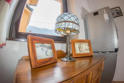 a table with three pictures and a lamp on it at Berghi Hotel and Apartments in Kranjska Gora