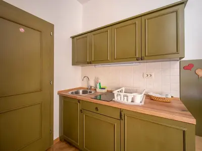a kitchen with green cabinets and a sink at Berghi Hotel and Apartments in Kranjska Gora