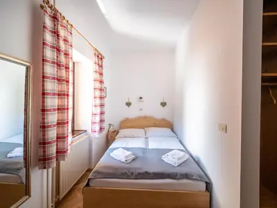 a small bedroom with a bed and a mirror at Berghi Hotel and Apartments in Kranjska Gora