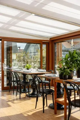 a dining room with tables and chairs and windows at Hotel Lipa in Kranjska Gora