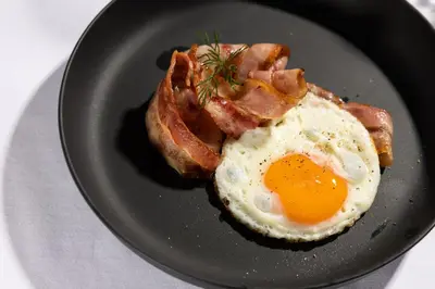 a plate with an egg and bacon and toast at Hotel Lipa in Kranjska Gora