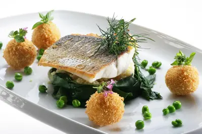 a plate of food with a piece of fish and vegetables at Hotel Lipa in Kranjska Gora