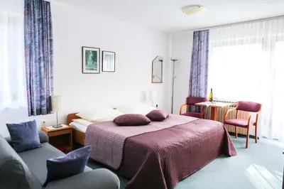 a bedroom with a bed with a purple blanket and chairs at Vila Romana in Kranjska Gora