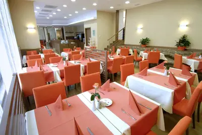a dining room with tables and orange chairs at Garni Hotel Savica - Sava Hotels & Resorts in Bled