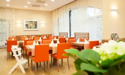 a dining room with tables and orange chairs at Garni Hotel Savica - Sava Hotels & Resorts in Bled