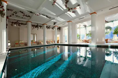 an indoor swimming pool with a large ceiling and columns at Grand Hotel Toplice - Small Luxury Hotels of the World in Bled