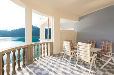 a porch with chairs and a table and a view of the water at Grand Hotel Toplice - Small Luxury Hotels of the World in Bled