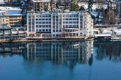 a large white building next to a body of water at Grand Hotel Toplice - Small Luxury Hotels of the World in Bled