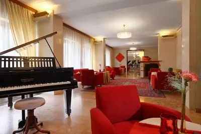 a living room with a piano and red chairs at Vila Bled in Bled