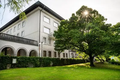 a white building with a tree in front of it at Vila Bled in Bled