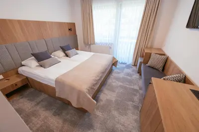 a hotel room with a large bed and a chair at Penzion Livada in Kranjska Gora