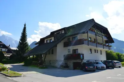 a large building with cars parked in a parking lot at Penzion Livada in Kranjska Gora
