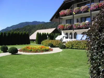 a building with a garden with flowers in a yard at Penzion Livada in Kranjska Gora