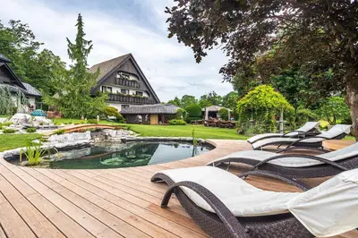 a deck with chairs next to a swimming pool at Alp Pension in Bled