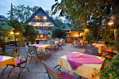 an outdoor patio with tables and chairs and a building at Alp Pension in Bled