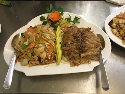 a plate of food with meat and vegetables on a table at Hotel Vila Emei in Maribor