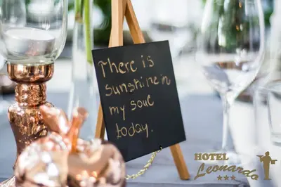 a sign sitting on a table with wine glasses at Hotel Leonardo in Slovenska Bistrica