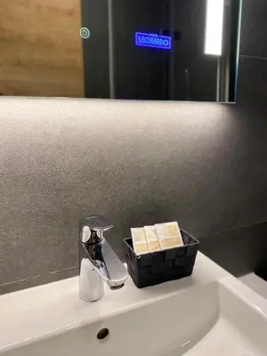 a bathroom sink with a soap dispenser and a mirror at Hotel Leonardo in Slovenska Bistrica