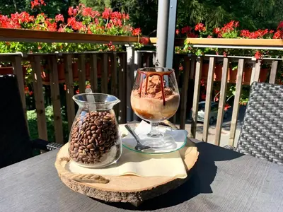 a table with a wine glass and a vase filled with food at Hotel Zarja in Pohorje