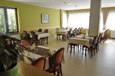a dining room with tables and chairs and windows at Hotel Zarja in Pohorje