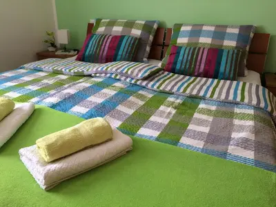 two beds with towels and pillows on a green floor at Apartments and Rooms Tavcar in Bled