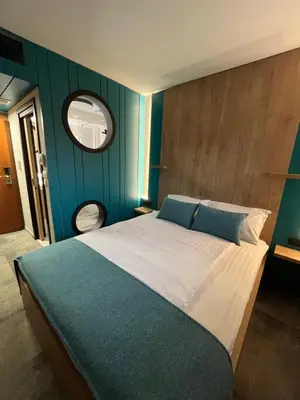 a bedroom with a large bed with a blue wall at Hotel MANTOVA Vrhnika in Vrhnika