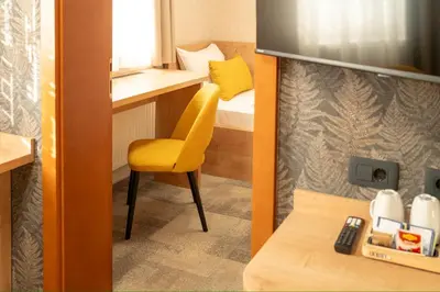 a small room with a yellow chair and a bed at Hotel MANTOVA Vrhnika in Vrhnika