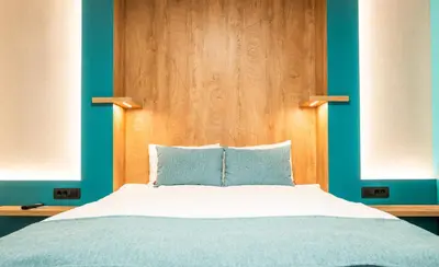 a bedroom with a bed with a wooden headboard at Hotel MANTOVA Vrhnika in Vrhnika