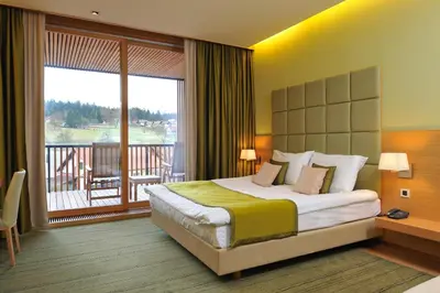 a bedroom with a large bed and a balcony at Hotel Balnea Superior - Terme Krka in Dolenjske Toplice