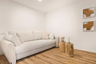 a white living room with a white couch and wood floors at Harmonija Padel&Wellness Resort in Mengeš