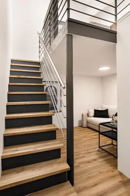 a staircase in a living room with a couch at Harmonija Padel&Wellness Resort in Mengeš