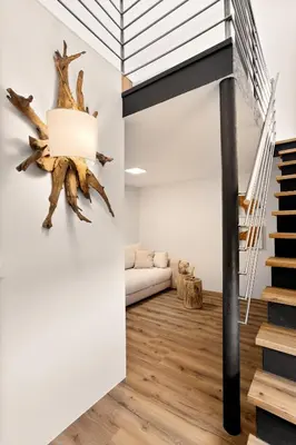 a room with a staircase and a living room with white walls at Harmonija Padel&Wellness Resort in Mengeš