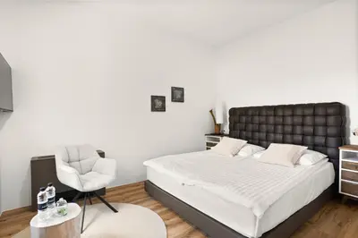 a bedroom with a bed and a chair at Harmonija Padel&Wellness Resort in Mengeš