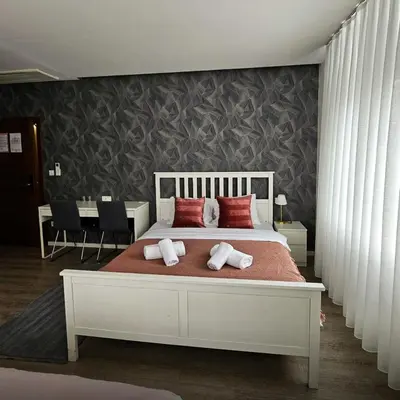 a bedroom with a white bed with red pillows at Hotel MOREA in Ljubljana