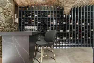 a bar with a black chair in front of a wall of wine bottles at Hotel MOREA in Ljubljana