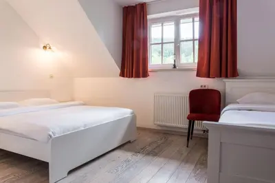 a bedroom with two beds and a red chair at Hotel MOREA in Ljubljana