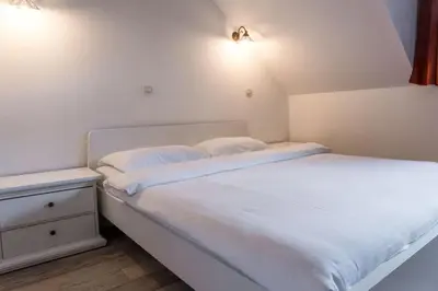 a white bed with two pillows and a night stand at Hotel MOREA in Ljubljana