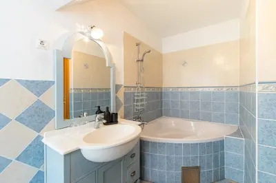 a blue tiled bathroom with a sink and a tub at Pension Lectar in Radovljica