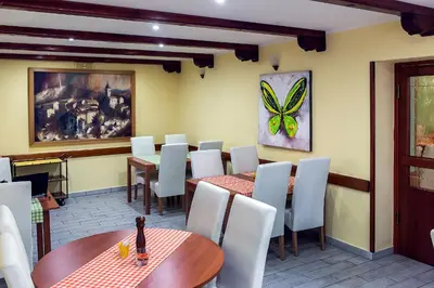 a restaurant with tables and white chairs and a butterfly painting at Gostilna Tratnik in Zoll