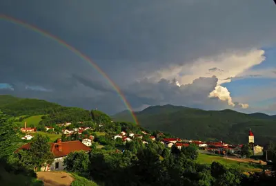a rainbow in the sky over a town with houses at Gostilna Tratnik in Zoll