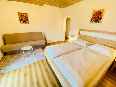 a bedroom with a large bed and a couch at Kunstelj Pension in Radovljica